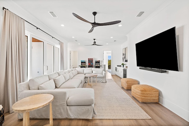 living room with light wood-type flooring, ceiling fan, and ornamental molding