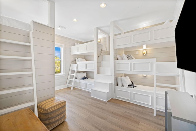 bedroom with light hardwood / wood-style floors and wooden walls