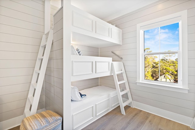 bedroom with wooden walls and light hardwood / wood-style flooring