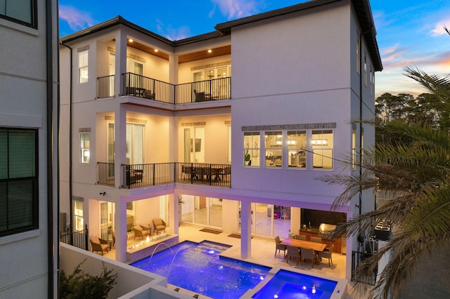 back house at dusk with outdoor lounge area, a pool with hot tub, pool water feature, and a patio area