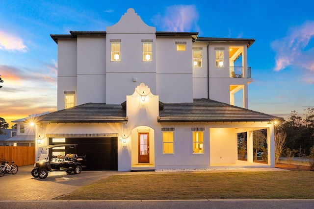 view of front of house with a garage, a lawn, and a balcony