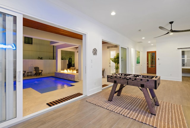 recreation room with ceiling fan and light hardwood / wood-style flooring