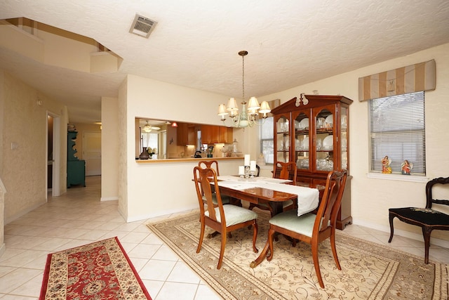 tiled dining area featuring a notable chandelier and a textured ceiling