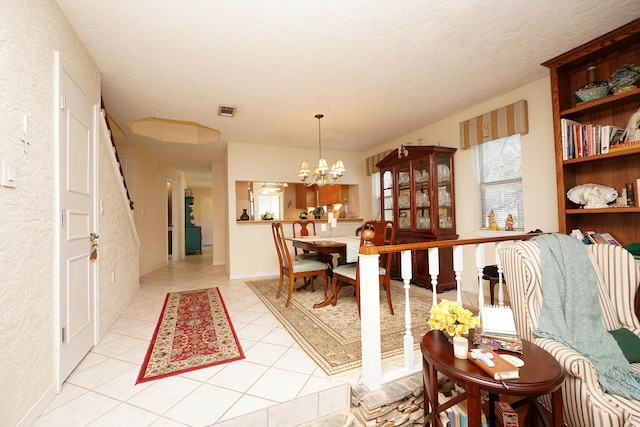 tiled dining area featuring a textured ceiling and a chandelier