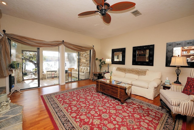 living room featuring a textured ceiling, wood-type flooring, and ceiling fan