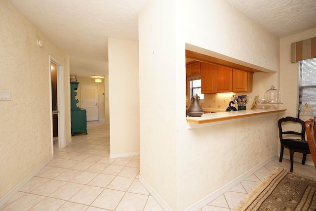 kitchen featuring light tile patterned floors, kitchen peninsula, and a textured ceiling