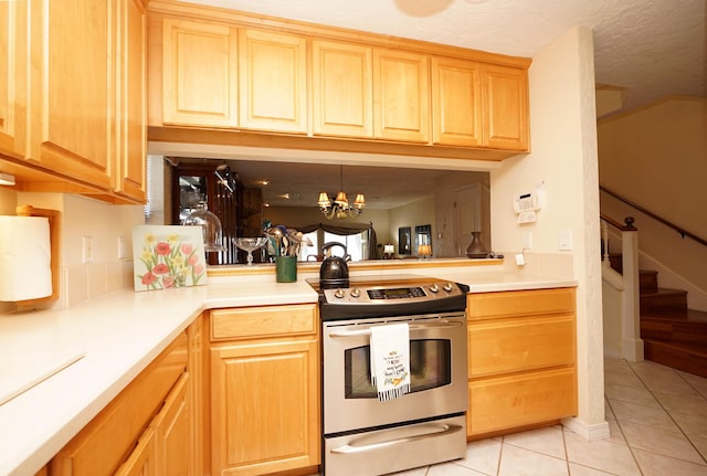 kitchen with stainless steel electric stove, pendant lighting, light tile patterned floors, and an inviting chandelier