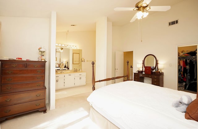 carpeted bedroom with high vaulted ceiling, a walk in closet, ceiling fan, ensuite bath, and a closet