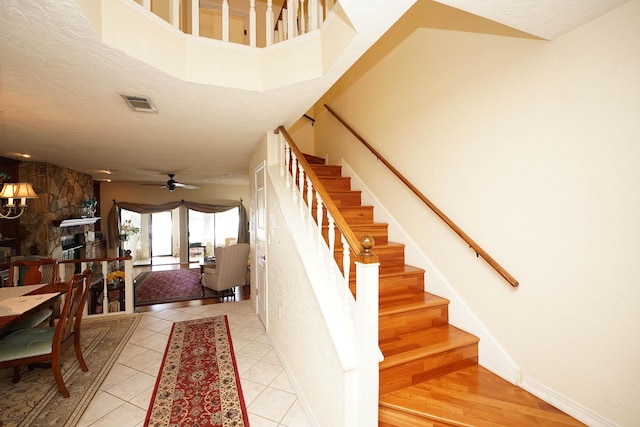 stairs featuring tile patterned flooring, a fireplace, and ceiling fan