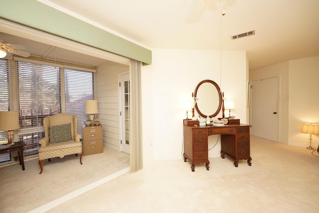 sitting room with ceiling fan, wooden walls, and light carpet