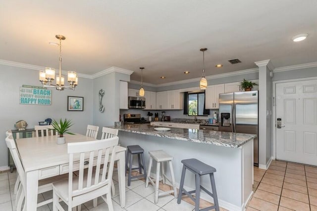 kitchen featuring light tile patterned floors, stainless steel appliances, hanging light fixtures, and dark stone counters