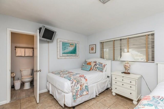 bedroom with ensuite bath and light tile patterned floors