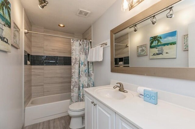 full bathroom featuring shower / bath combo, vanity, hardwood / wood-style flooring, and toilet