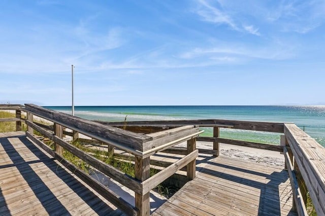 wooden deck featuring a water view and a beach view