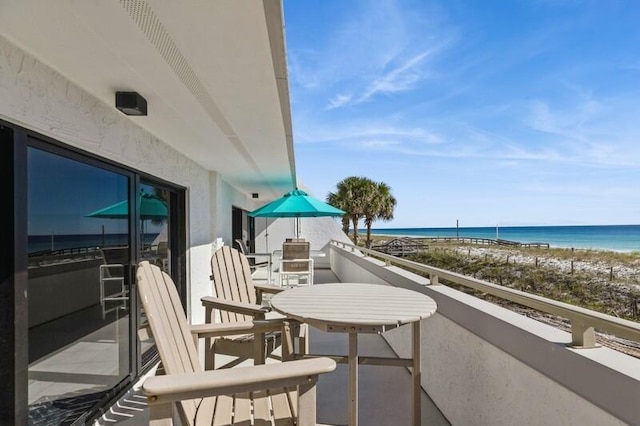 balcony with a water view and a view of the beach