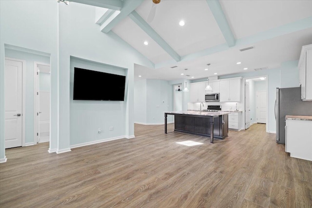 kitchen featuring stainless steel appliances, a kitchen island with sink, a breakfast bar, white cabinetry, and light wood-type flooring