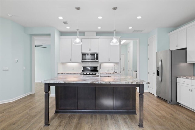 kitchen featuring pendant lighting, appliances with stainless steel finishes, white cabinetry, and an island with sink