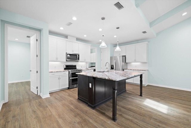 kitchen featuring white cabinetry, stainless steel appliances, and a center island with sink