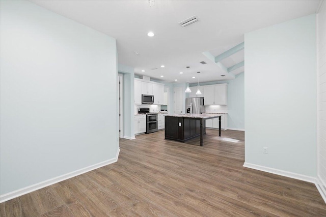 kitchen featuring a breakfast bar area, a kitchen island, white cabinetry, appliances with stainless steel finishes, and decorative light fixtures