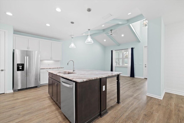 kitchen with stainless steel appliances, white cabinetry, sink, a kitchen island with sink, and lofted ceiling with beams