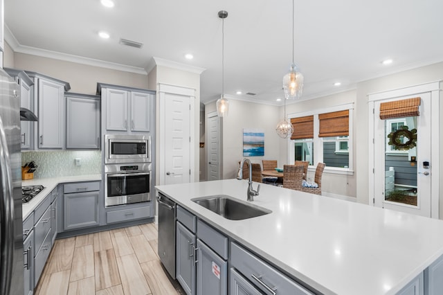 kitchen featuring sink, an island with sink, hanging light fixtures, gray cabinets, and stainless steel appliances