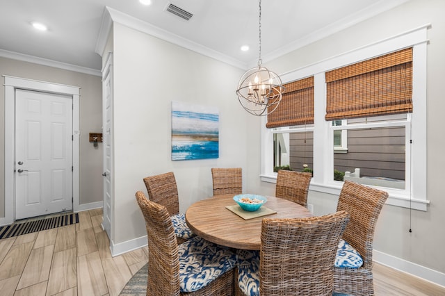 dining area with light hardwood / wood-style flooring, ornamental molding, and an inviting chandelier