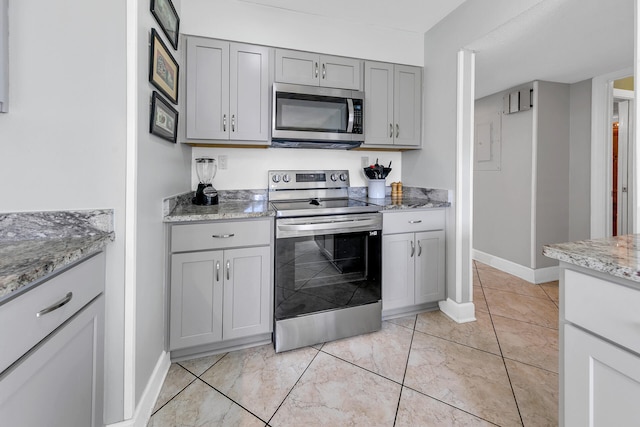 900 Gulf Shore Dr Unit 03, Destin, FL 32541 - kitchen with stainless steel appliances, gray cabinets, baseboards, and light stone counters
