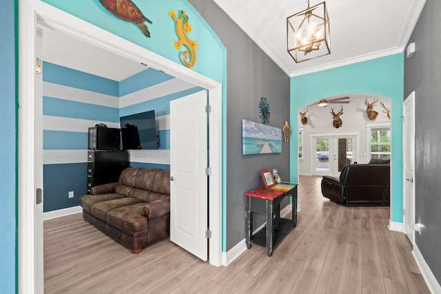 hall featuring a chandelier, light wood-type flooring, crown molding, and french doors