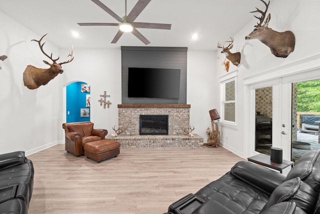 living room featuring a brick fireplace, ceiling fan, french doors, and light hardwood / wood-style flooring