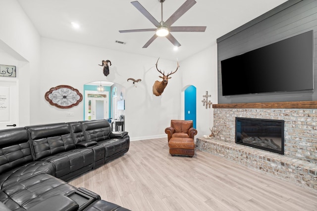 living room with light hardwood / wood-style floors, a brick fireplace, and ceiling fan