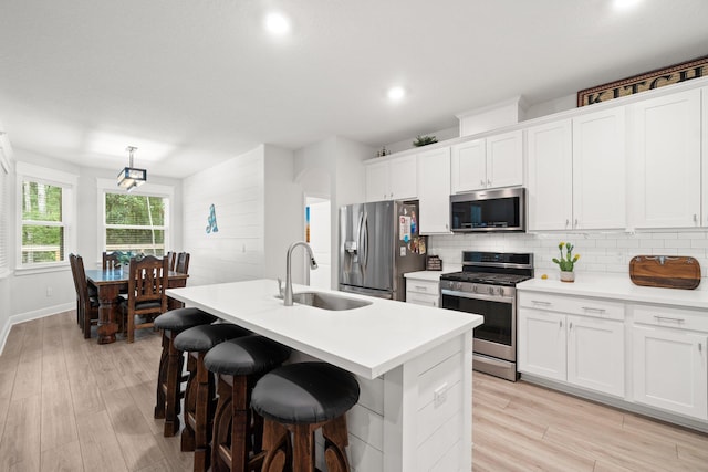 kitchen featuring white cabinetry, sink, a center island with sink, and appliances with stainless steel finishes