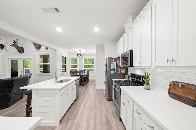 kitchen featuring sink, appliances with stainless steel finishes, a kitchen bar, white cabinets, and light wood-type flooring