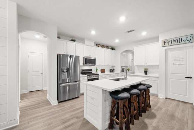 kitchen featuring white cabinets, sink, appliances with stainless steel finishes, and an island with sink