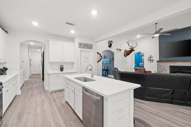 kitchen featuring white cabinets, a fireplace, sink, a center island with sink, and dishwasher