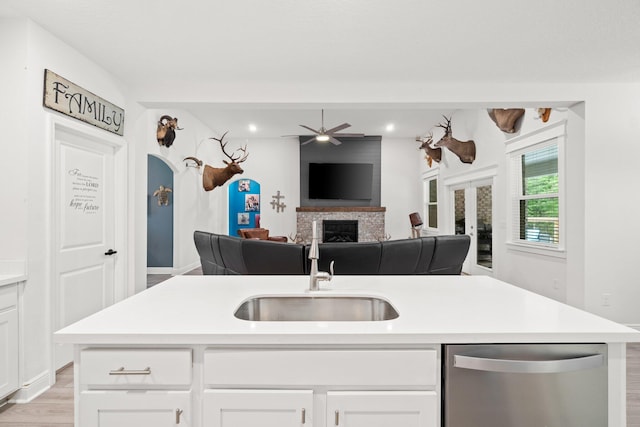 kitchen with white cabinets, dishwasher, sink, and an island with sink