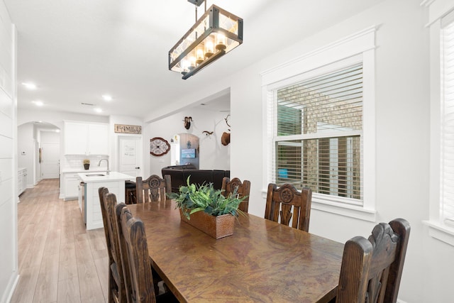 dining room featuring light wood-type flooring, sink, and a chandelier