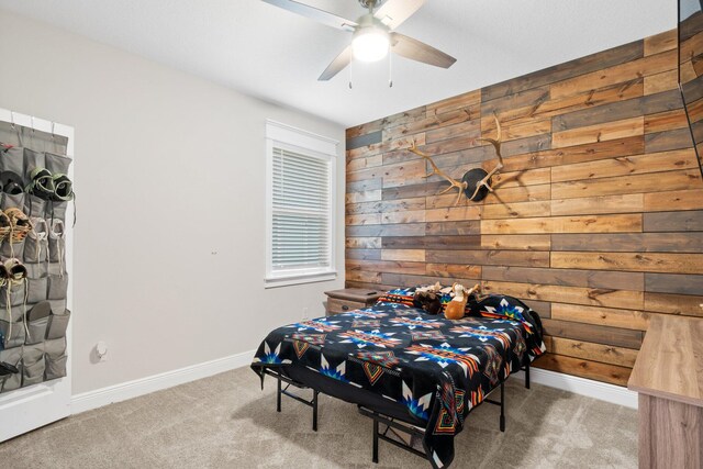 bedroom with carpet flooring, ceiling fan, and wooden walls