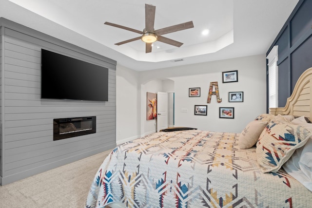 bedroom featuring carpet flooring, a raised ceiling, ceiling fan, and a fireplace