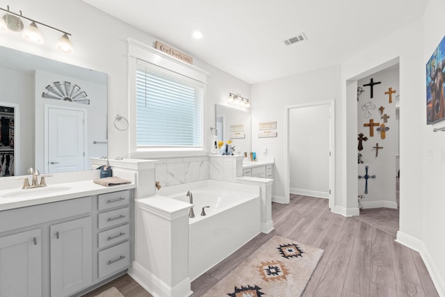 bathroom with vanity, wood-type flooring, and a bath