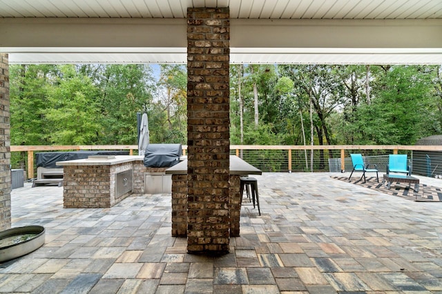 view of patio featuring area for grilling, exterior bar, and an outdoor kitchen