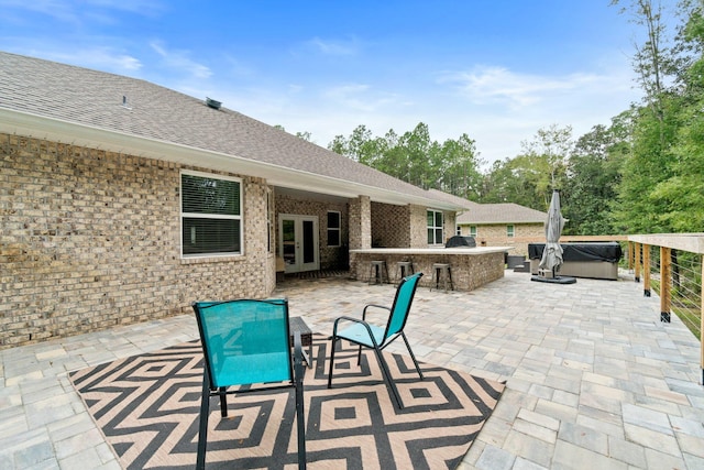 view of patio with french doors, a bar, a grill, exterior kitchen, and a hot tub