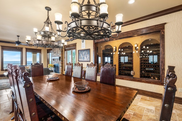 dining area featuring stone tile floors, ceiling fan with notable chandelier, and a textured wall