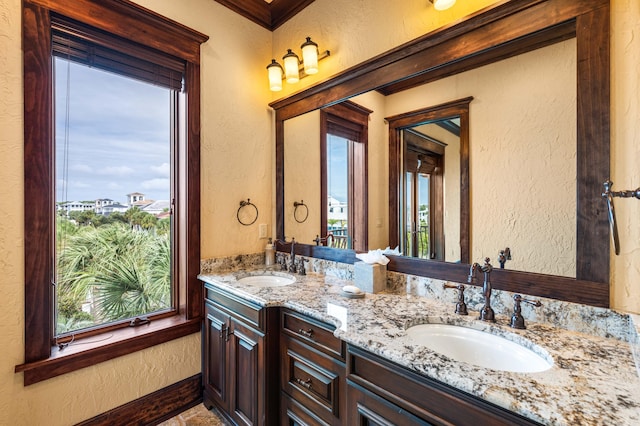 bathroom featuring double vanity, a textured wall, and a sink