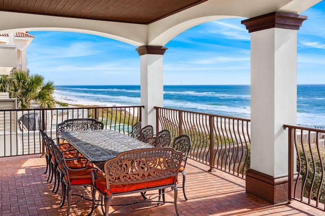 exterior space featuring a view of the beach, outdoor dining area, and a water view