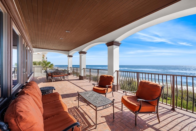 view of patio / terrace featuring a view of the beach, a balcony, a water view, and an outdoor hangout area