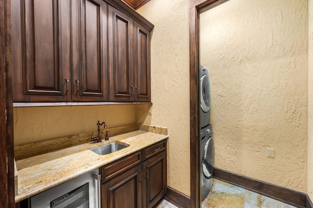 interior space featuring stacked washer and dryer, a sink, light stone counters, dark brown cabinets, and a textured wall