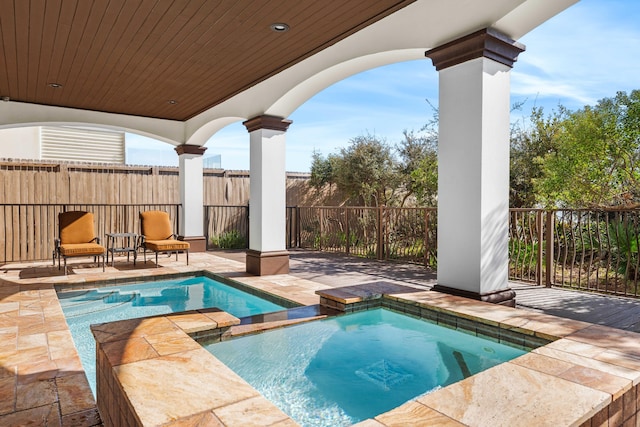 view of swimming pool with a patio area, a pool with connected hot tub, and fence