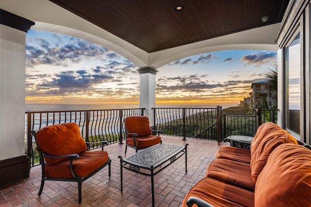 patio terrace at dusk featuring an outdoor living space and a water view