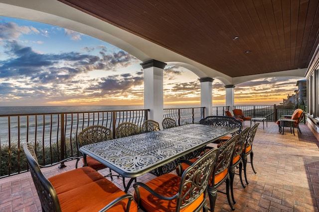 patio terrace at dusk with outdoor dining space and a water view