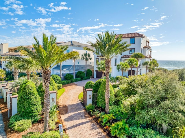 exterior space featuring a fenced front yard, decorative driveway, and a water view